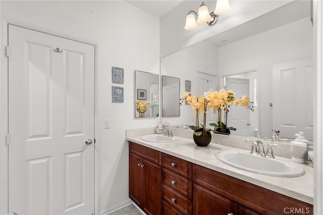 full bath featuring baseboards, double vanity, and a sink