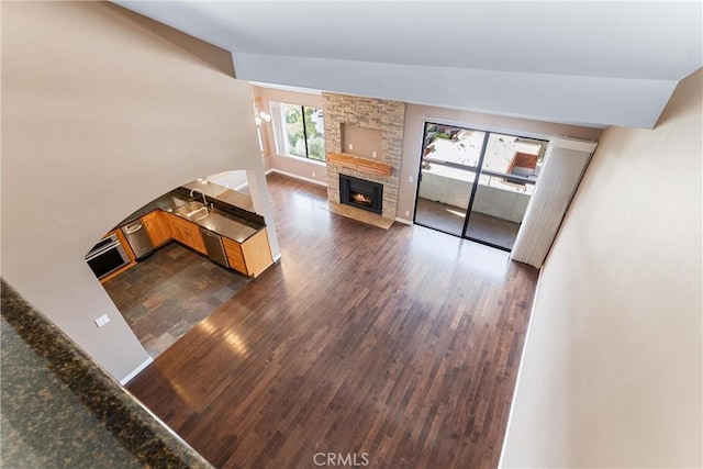 unfurnished living room with a fireplace, dark wood-style flooring, and lofted ceiling