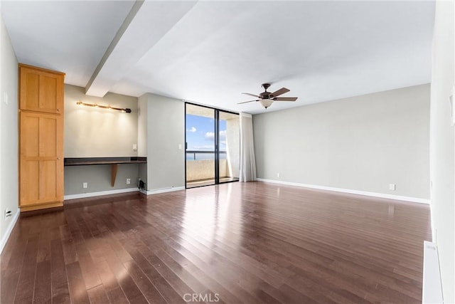 unfurnished living room featuring dark wood finished floors, a ceiling fan, baseboards, and expansive windows