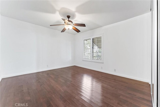 spare room with dark wood-style floors, ceiling fan, and baseboards