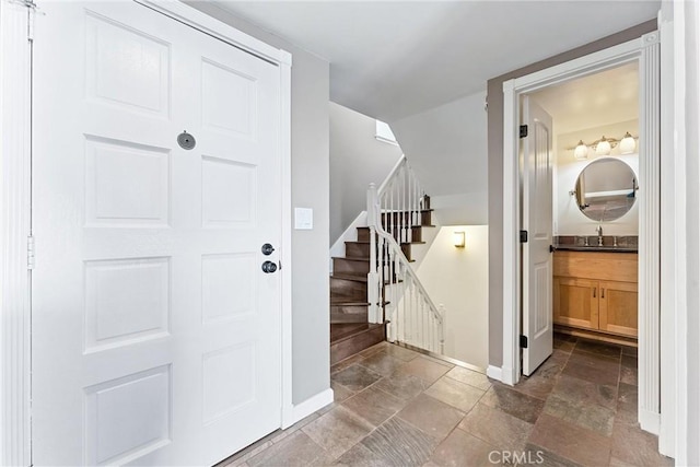 foyer entrance featuring stairs, baseboards, and stone tile flooring
