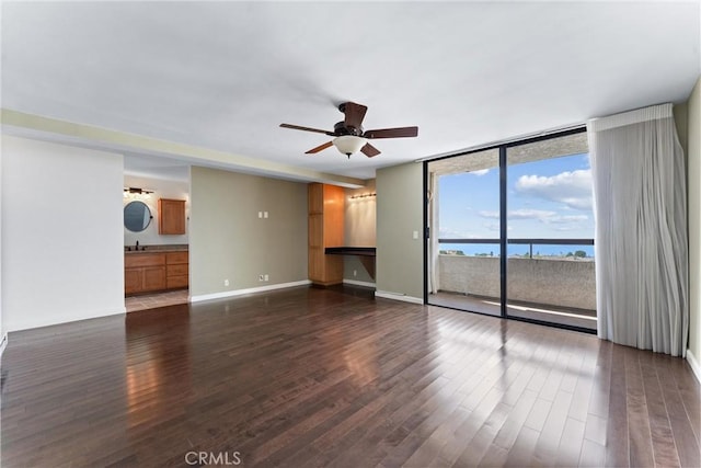 unfurnished living room with ceiling fan, dark wood-style flooring, floor to ceiling windows, and baseboards