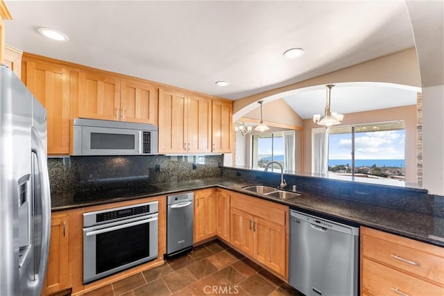 kitchen featuring appliances with stainless steel finishes, a sink, a chandelier, arched walkways, and backsplash