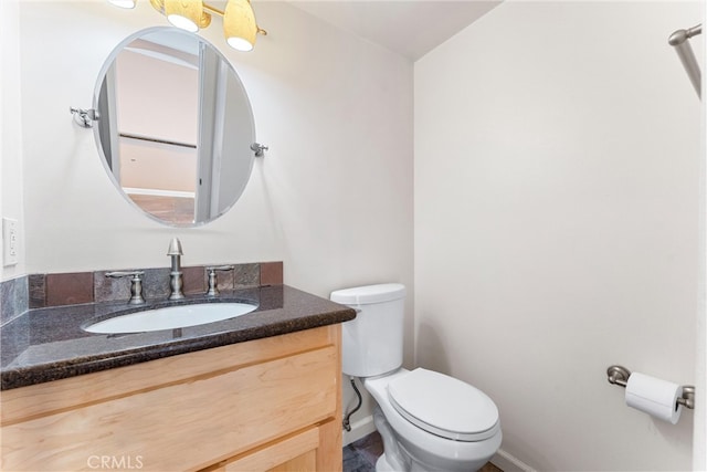 bathroom featuring toilet, vanity, and baseboards