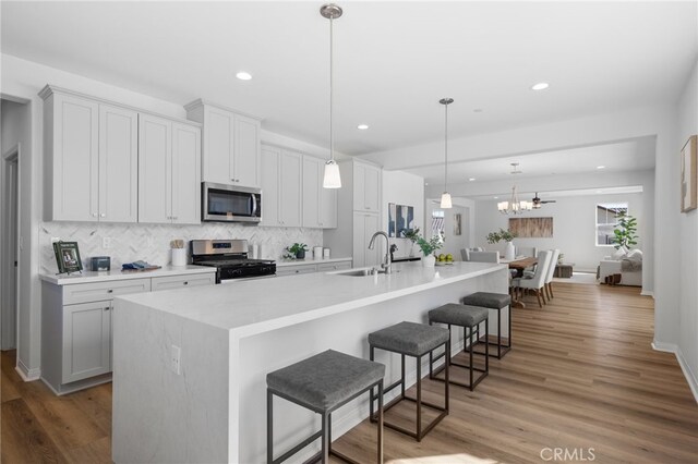 kitchen featuring stainless steel appliances, a kitchen breakfast bar, a sink, tasteful backsplash, and recessed lighting