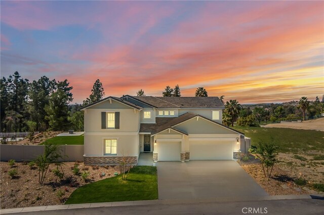 traditional-style house with driveway, stone siding, fence, a garage, and stucco siding