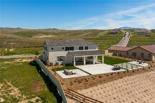 back of property with a fenced backyard, stucco siding, a patio area, a lawn, and a mountain view