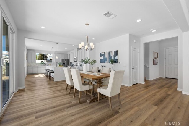 dining area featuring a notable chandelier, light wood-style flooring, and recessed lighting