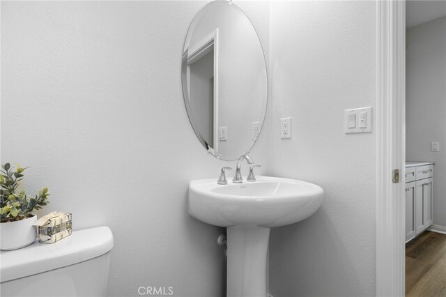 half bathroom featuring wood finished floors and toilet