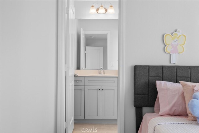 interior space with connected bathroom, a sink, and light wood finished floors