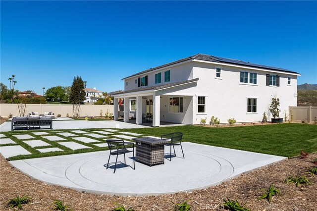 back of house featuring a fenced backyard, stucco siding, solar panels, a patio area, and a lawn