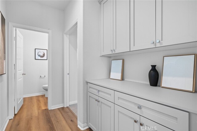 corridor with light wood-style floors and baseboards