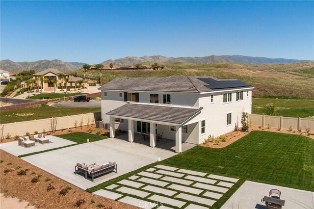 back of property featuring a fenced backyard, solar panels, a mountain view, and a patio area