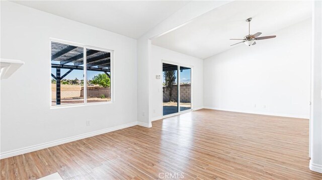 spare room featuring vaulted ceiling, wood finished floors, a ceiling fan, and baseboards