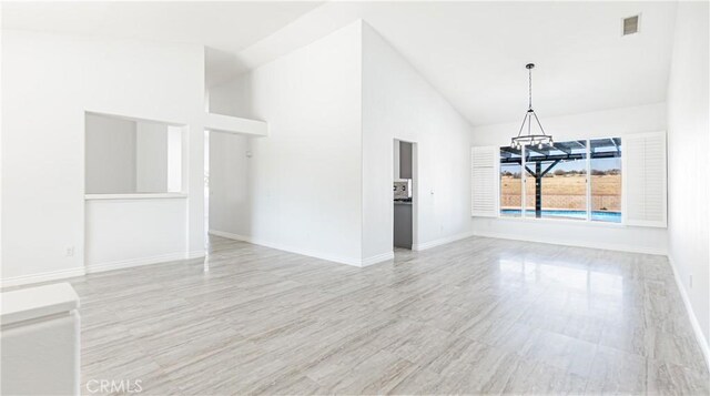 unfurnished dining area with high vaulted ceiling, baseboards, a chandelier, and visible vents