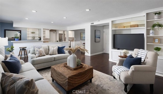 living area featuring dark wood finished floors, baseboards, recessed lighting, built in shelves, and ornamental molding