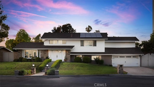 traditional home featuring solar panels, a front lawn, fence, and concrete driveway
