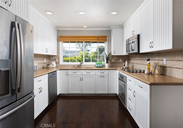 kitchen featuring crown molding, tasteful backsplash, a sink, white cabinets, and appliances with stainless steel finishes