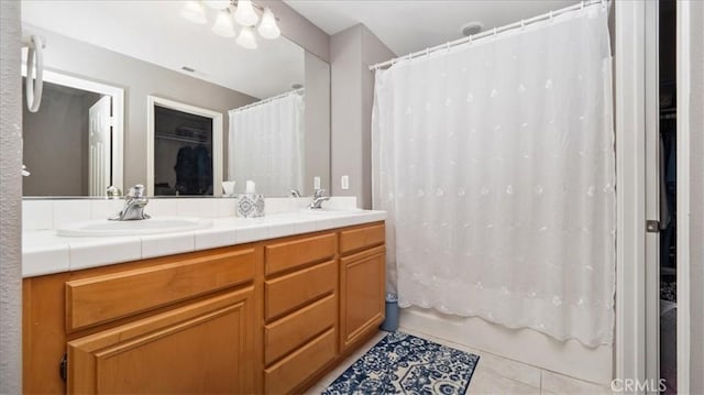 full bath with double vanity, tile patterned floors, shower / tub combo with curtain, and a sink