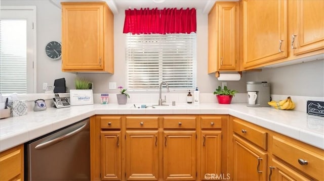 kitchen featuring light countertops, stainless steel dishwasher, and a sink