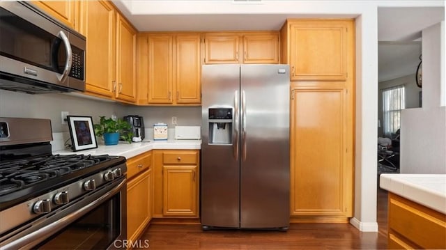 kitchen featuring tile countertops, appliances with stainless steel finishes, and dark wood finished floors