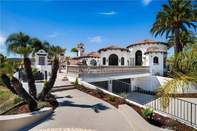 mediterranean / spanish-style home featuring stucco siding, a tiled roof, and a fenced front yard