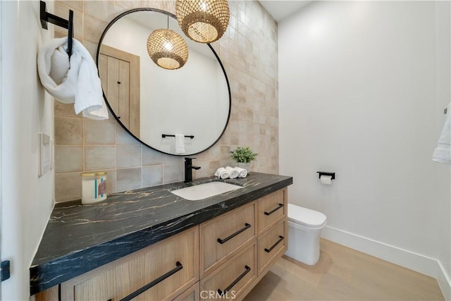 bathroom featuring wood finished floors, vanity, baseboards, backsplash, and toilet