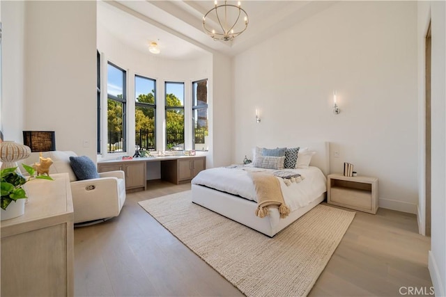 bedroom with an inviting chandelier, light wood-style floors, and baseboards