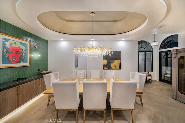 dining area featuring a tray ceiling, visible vents, and an inviting chandelier