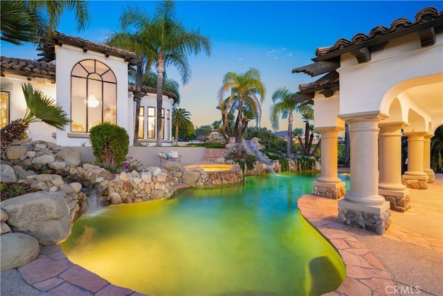 pool featuring a water slide and an in ground hot tub