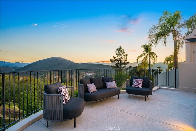 patio terrace at dusk featuring a mountain view, a balcony, and outdoor lounge area