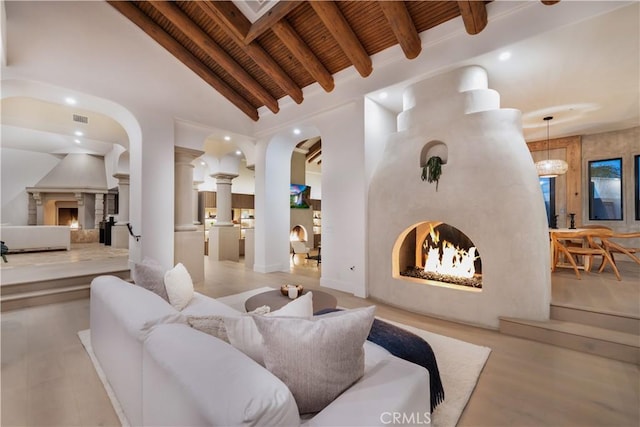living room featuring vaulted ceiling with beams, a lit fireplace, wooden ceiling, visible vents, and recessed lighting
