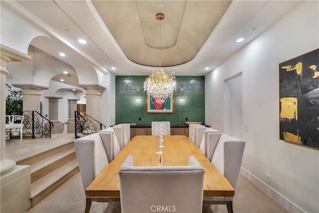 dining space featuring baseboards, recessed lighting, a notable chandelier, and ornate columns