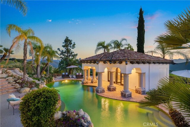 pool at dusk featuring an outdoor pool and a patio