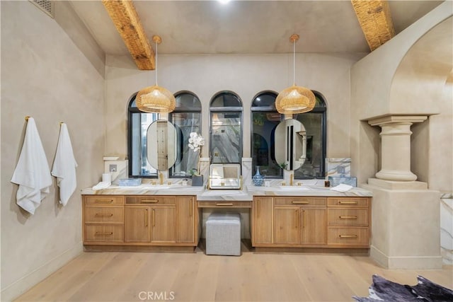 full bath with wood finished floors, beamed ceiling, double vanity, baseboards, and visible vents