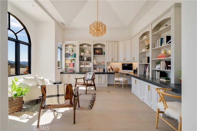 kitchen featuring dark countertops, open shelves, built in desk, a chandelier, and light wood-style flooring
