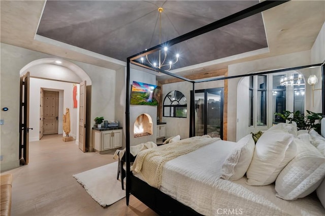 bedroom with baseboards, wood finished floors, a chandelier, and a raised ceiling