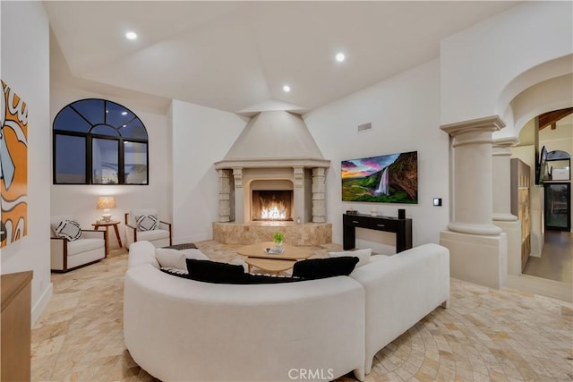 living area with decorative columns, baseboards, lofted ceiling, visible vents, and recessed lighting