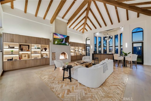 living room with high vaulted ceiling, a notable chandelier, and a lit fireplace