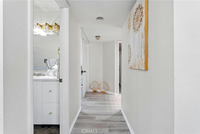 hallway featuring light wood finished floors and baseboards
