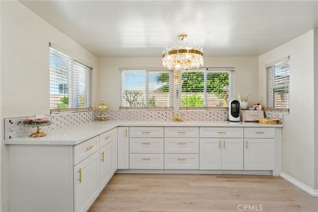 kitchen with light wood-type flooring, a notable chandelier, a wealth of natural light, and white cabinets