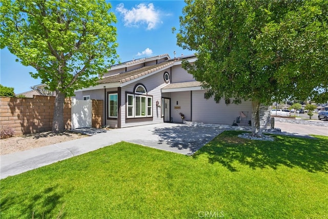 rear view of property featuring a lawn and fence