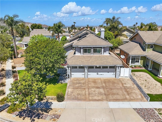 view of front of property featuring a chimney, a residential view, driveway, and an attached garage