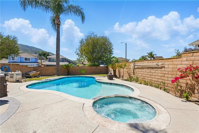 view of swimming pool with a fenced backyard, a pool with connected hot tub, and a patio area