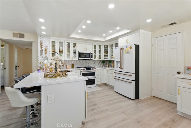 kitchen with a kitchen breakfast bar, visible vents, light wood-style floors, and white appliances