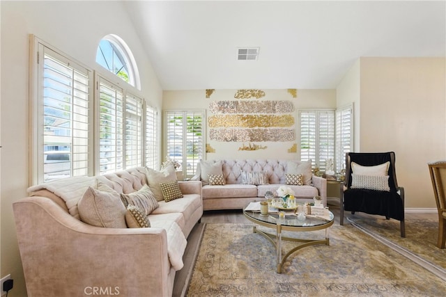 living room featuring visible vents, plenty of natural light, and high vaulted ceiling