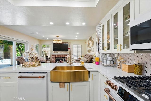 kitchen with a sink, a brick fireplace, white appliances, light countertops, and open floor plan