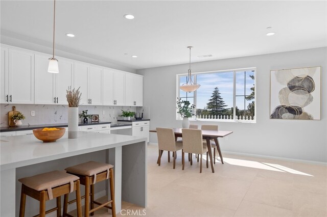 kitchen featuring decorative backsplash, white cabinetry, a breakfast bar area, and recessed lighting