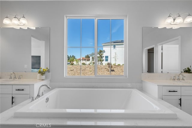 full bathroom with two vanities, a bath, and a sink
