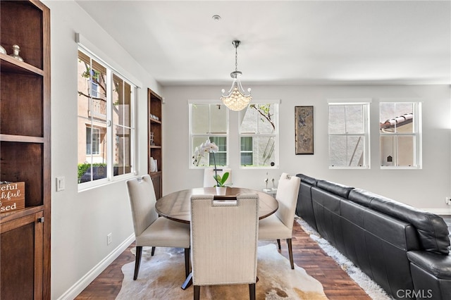 dining room featuring baseboards, a notable chandelier, and wood finished floors